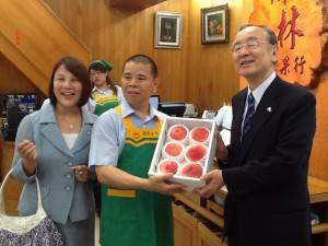 山梨縣知事橫內正明(右)推銷山梨品牌水蜜桃(圖左起分別為)僑務委員鄭玉蘭和水果店店長
