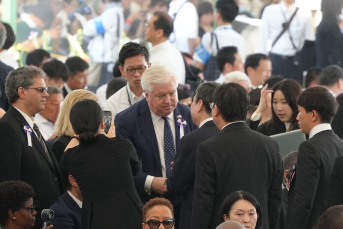 米国のジョージ・グラス駐日大使(白髪の男性)と握手を交わす李逸洋駐日代表 米国のジョージ・グラス駐日大使(白髪の男性)と握手を交わす李逸洋駐日代表